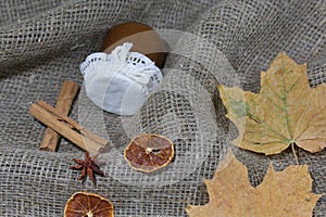 Jar of jam and dried maple leaves on a rough linen cloth. Nearby are cinnamon, dried orange slices and anise. Autumn still life