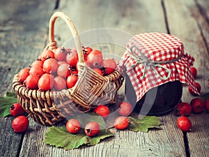 Jar of jam and hawthorn berries in basket on table