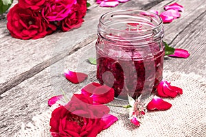 Jar of jam of rose petals on a wooden table with flowers of roses. Flower confiture. Healthy food