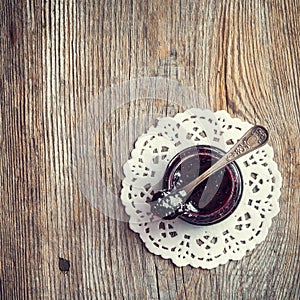 Jar of jam with spoon on old wooden table.