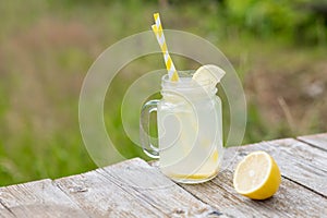 Jar with lemon water and lemon on wooden table. Cocktail. Summer relax. Copy space.