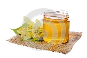 Jar of linden honey and flowering linden on white