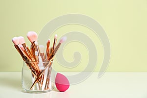 Jar with makeup brushes and sponge on table