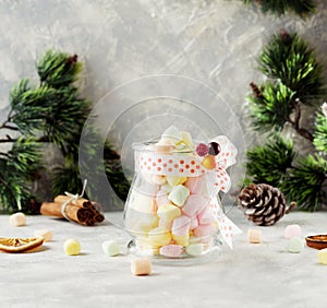 Jar with marshmallows for Christmas and New Year on a wooden white table, selective focus