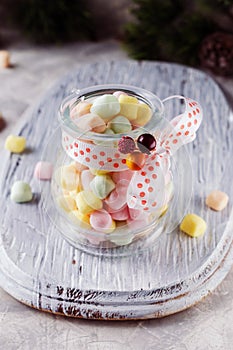 Jar with marshmallows for Christmas and New Year on a wooden white table, selective focus