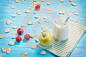 Jar of milk and green apple, striped napkin on table.