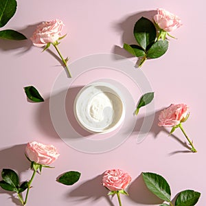 Jar of moisturizer cream and rose flowers on pink backrground. SPA roses cosmetics concept