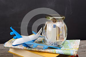 Jar with money for a travel, maps, passport, and other stuff for adventure