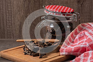 Jar with mushrooms, a dish towel and dried pine mushrooms in a small plate on a board