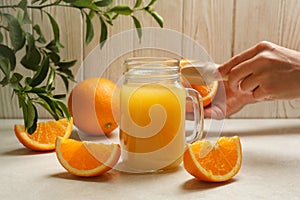 Jar with orange juice against wooden background with female hand hold juicer and orange