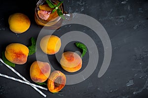 Jar of peach iced tea with fresh peaches on the rustic background