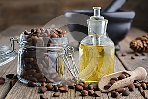 Jar of pine nuts and pine nuts essential oil bottle. Black mortar on background