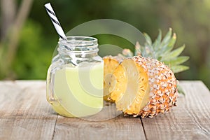 A jar of pineapple juice with a raw pine apple