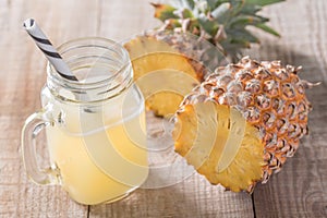 A jar of pineapple juice with a raw pine apple