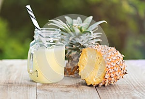 A jar of pineapple juice with a raw pine apple