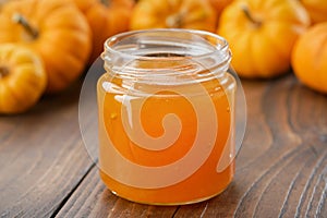 Jar of  pumpkin jam on kitchen table. Pumpkins in the background