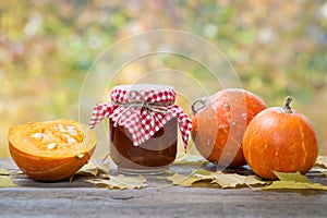 Jar of pumpkin jam, puree or sauce and small ripe pumpkins