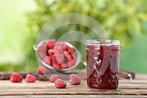 Jar with raspberry jam on table