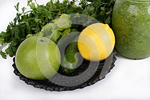 Jar of raw green vegetable smoothie juice with lemon, cucumbers, apple, apio and parsley, on white background