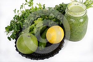 Jar of raw green vegetable smoothie juice with lemon, cucumbers, apple, apio and parsley, on white background