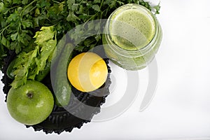 Jar of raw green vegetable smoothie juice with lemon, cucumbers, apple, apio and parsley, on white background
