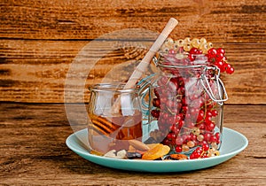 Jar of red currants, honey, dried fruits and nuts on wooden background. Copy space. Immunity boosting