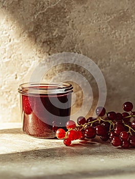 Jar of redcurrant jam next to fresh redcurrants