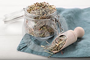 Jar and scoop with aromatic dried lemongrass on white table