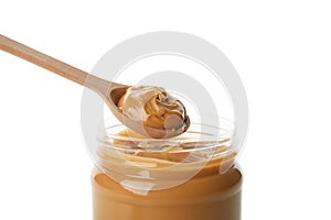 Jar and spoon with peanut butter isolated on white background