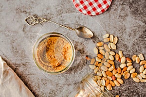 Jar and spoon of peanut butter and peanuts on dark wooden background from top view.Kinfolk and comfort food atmosphere concept