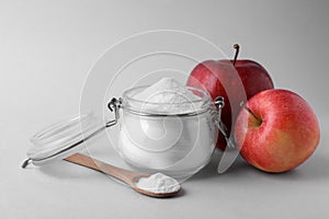 Jar, spoon with sweet fructose powder and ripe apples on white background