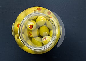 Jar of stuffed green olives in brine close up top view photo wit