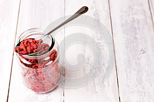 Jar of superfood goji berries on white wood