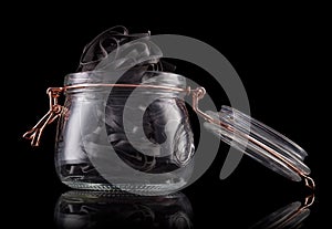 Jar of tagliatelle pasta nests on wooden table isolated on black background