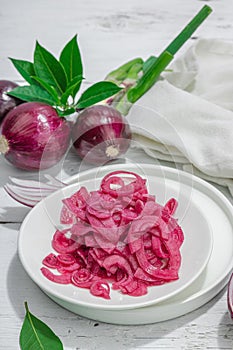 Jar with tasty pickled onions on black table. Cutlery, served meal ready to eat, trendy stand