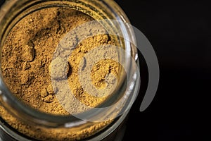 A jar of turmeric spice on a black table, close up, isolated