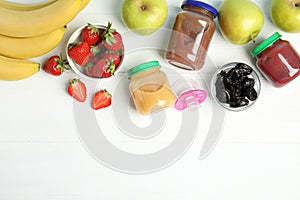 Jars with baby food and fresh ingredients on wooden table, flat lay. Space for text