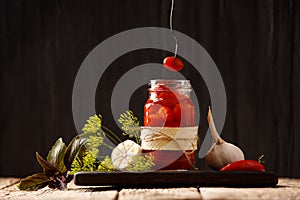 Jars with canned tomatoes on wooden background