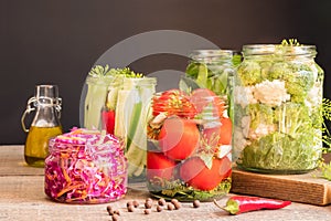 Jars with canned vegetables on wooden kitchen table. Food preservation and conservation concept