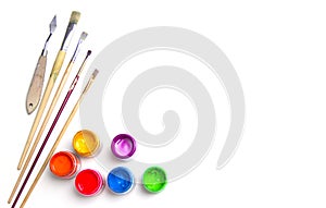 Jars with colorful art paint and brushes are on a white background