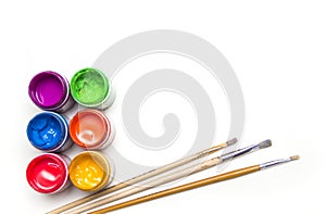 Jars with colorful art paint and brushes are on a white background