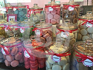 Jars of colorful macaroon cakes on display in store front photo