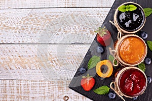 Jars with delicious summer fruits jam - top view