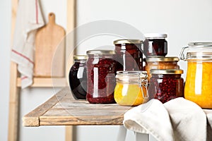 Jars with different jams on wooden table