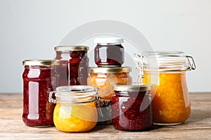 Jars with different jams on wooden table
