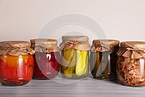 Jars with different preserved vegetables on wooden table