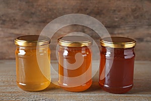 Jars with different types of organic honey on table