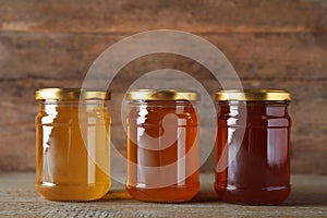 Jars with different types of organic honey on table