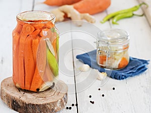 Jars of fermented peppers carrots, garlic and ginger on a wooden stand. Filled with brine. Harvesting for the winter. Canned