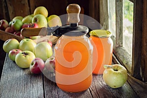 Jars of fresh apple juice, apple fruits and can lid closing machine for canning.